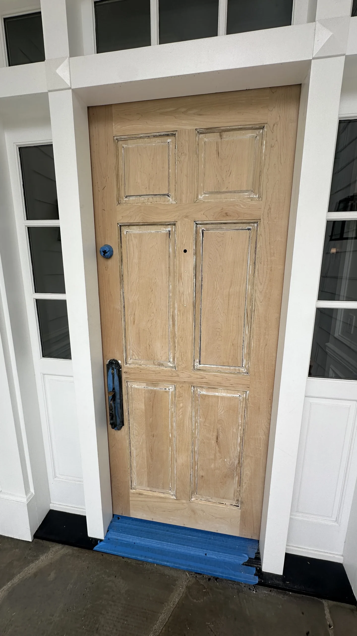 Wood entry door with side windows in a repaired frame, ready for finish