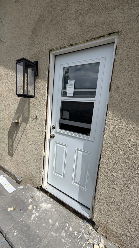 White exterior door installed next to a wall sconce