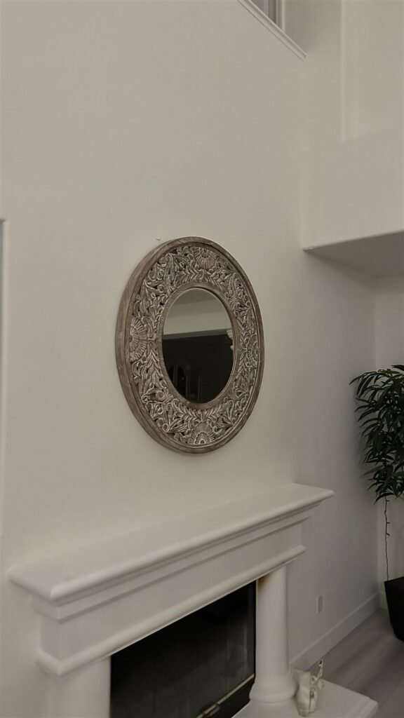 Round mirror hung above a fireplace in Los Angeles