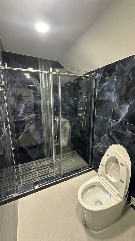 Dark marble shower with sliding glass door in Los Angeles