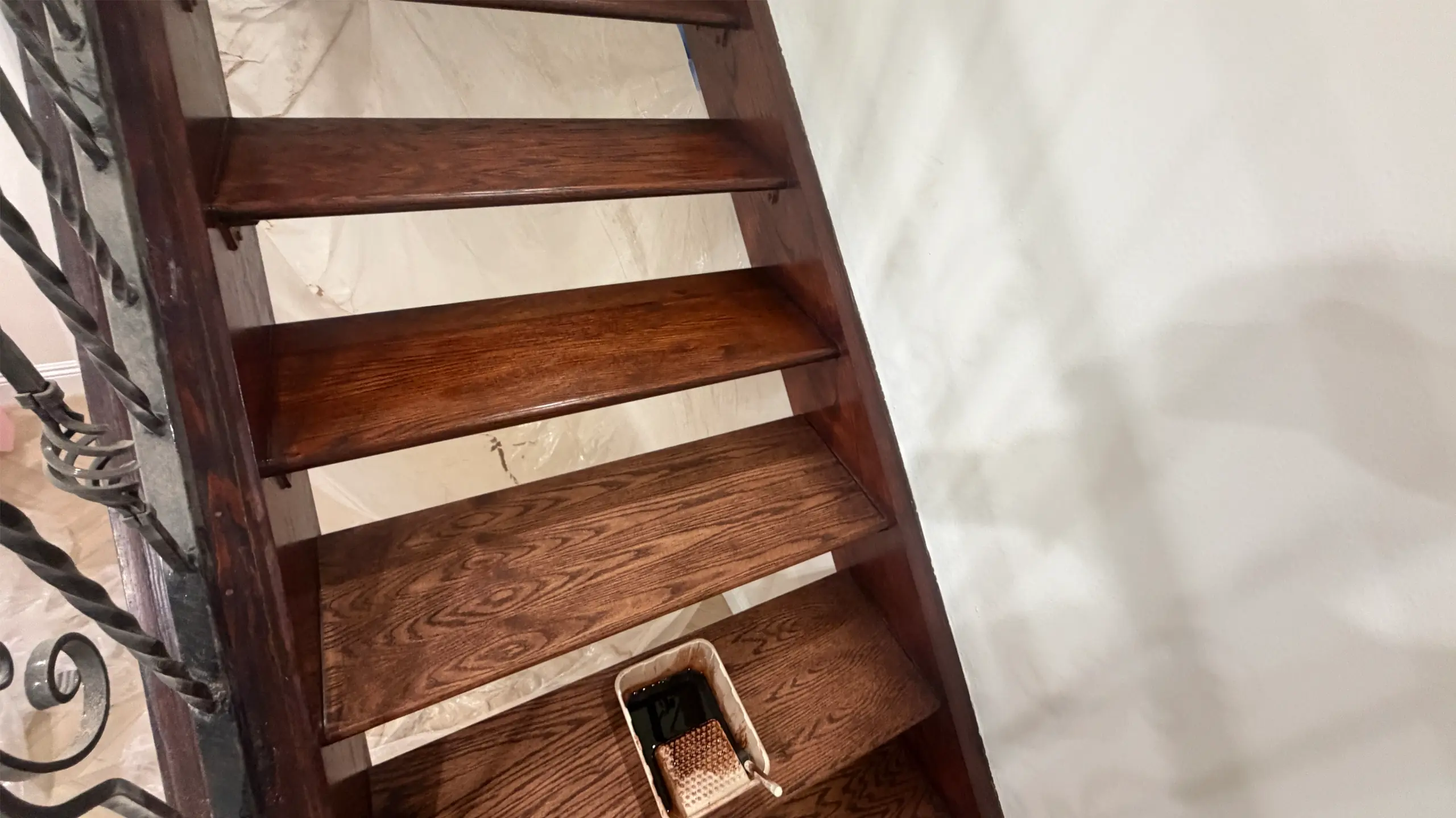 Refinished wooden staircase with a wrought-iron railing in a Los Angeles home - stair and railing repair